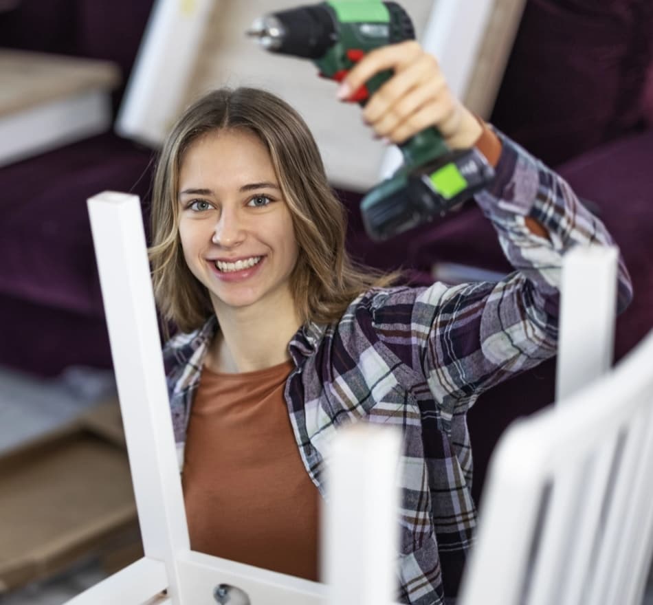 Young woman with a drill assembling furniture, representing DIY enthusiasts seeking contractor help